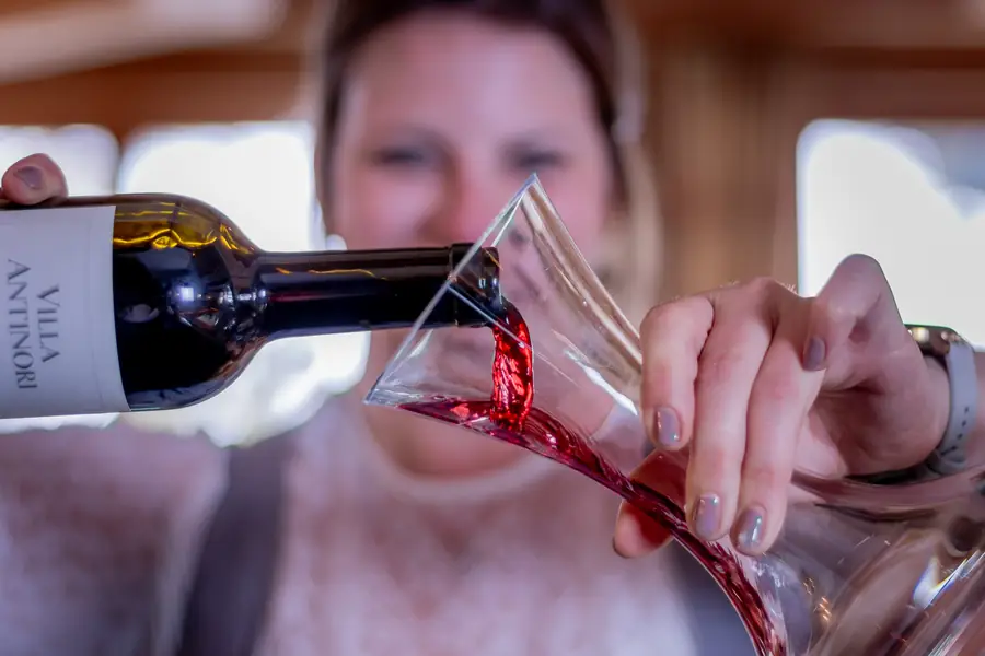 Rotwein wird in eine gläserne Karaffe geschenkt