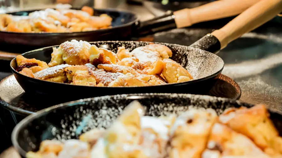 Kaiserschmarrn mit Staubzucker in gusseisernen Pfannen